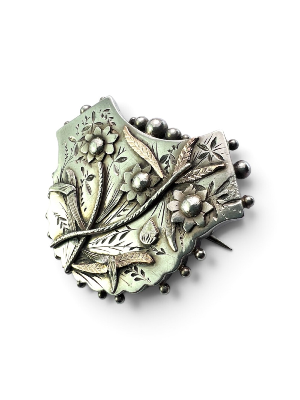 A Victorian silver shield-shaped brooch decorated with applied rose gold flowers, hand engraving, and a beaded outer rim. View IV