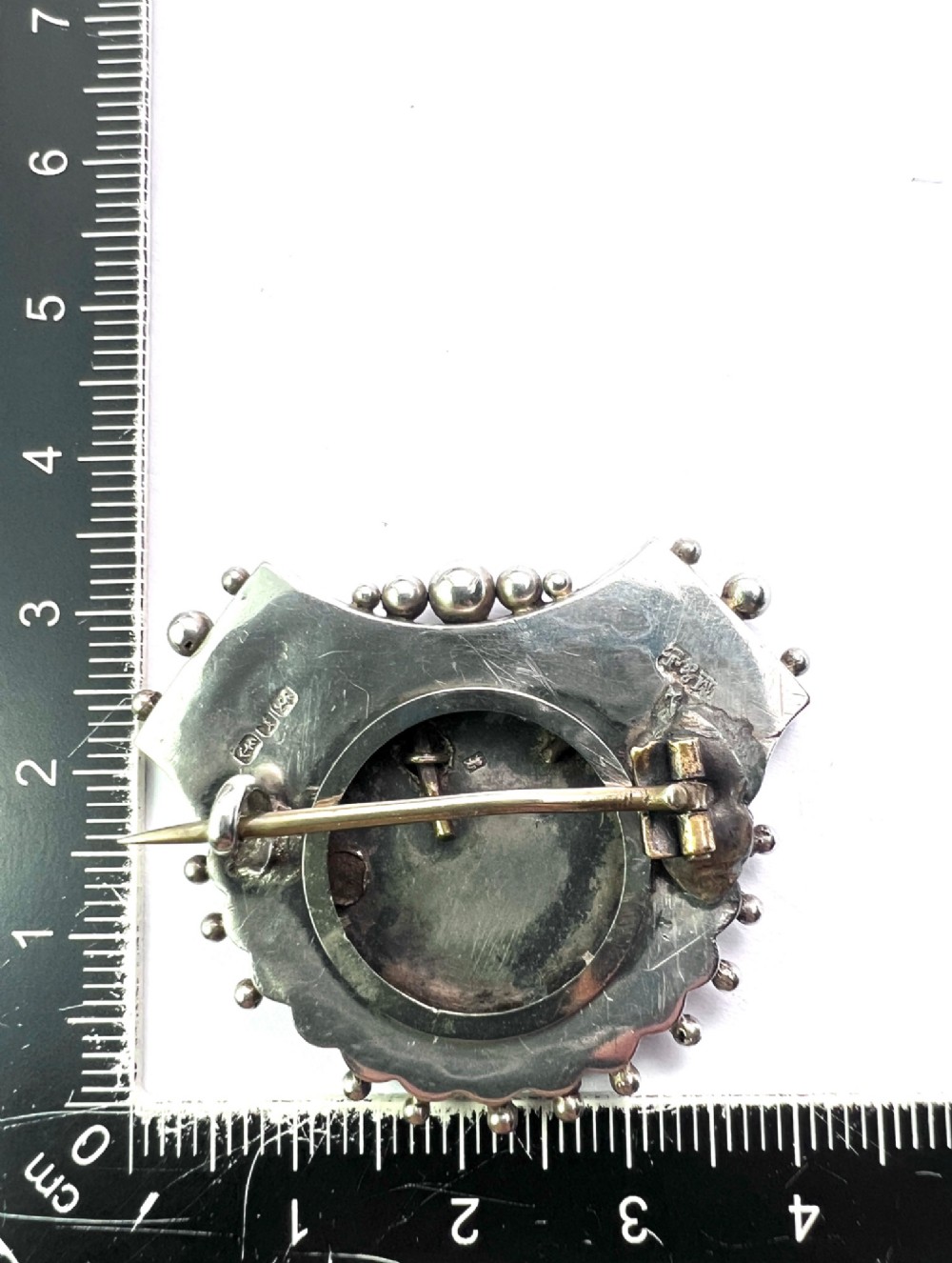 A Victorian silver shield-shaped brooch decorated with applied rose gold flowers, hand engraving, and a beaded outer rim. View V
