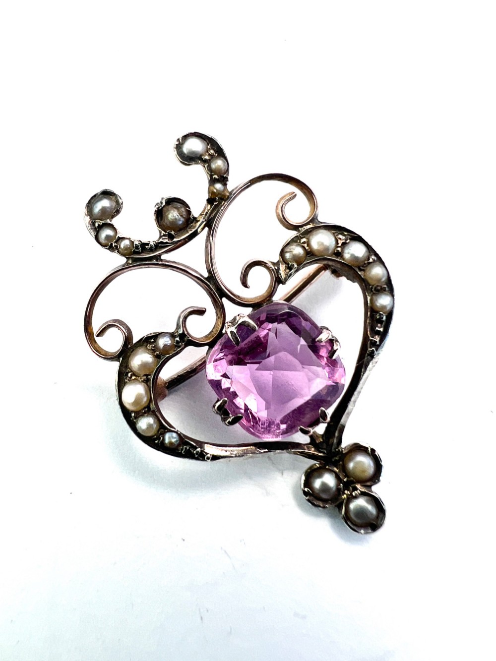 An Edwardian gold openwork scrollwork brooch featuring a central cushion-cut pink tourmaline surrounded by accent seed pearls. View II