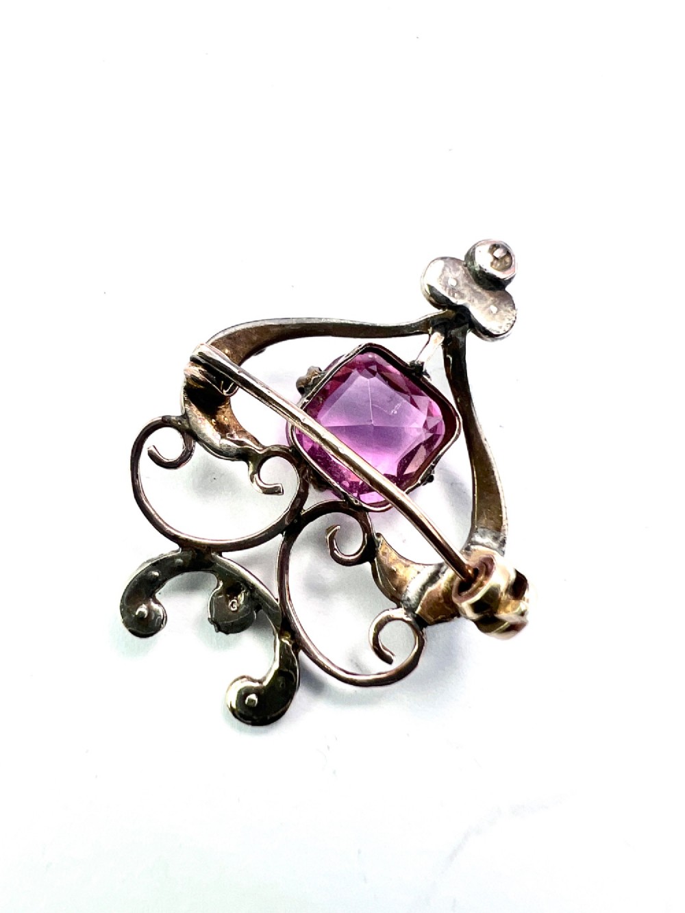 An Edwardian gold openwork scrollwork brooch featuring a central cushion-cut pink tourmaline surrounded by accent seed pearls. View III