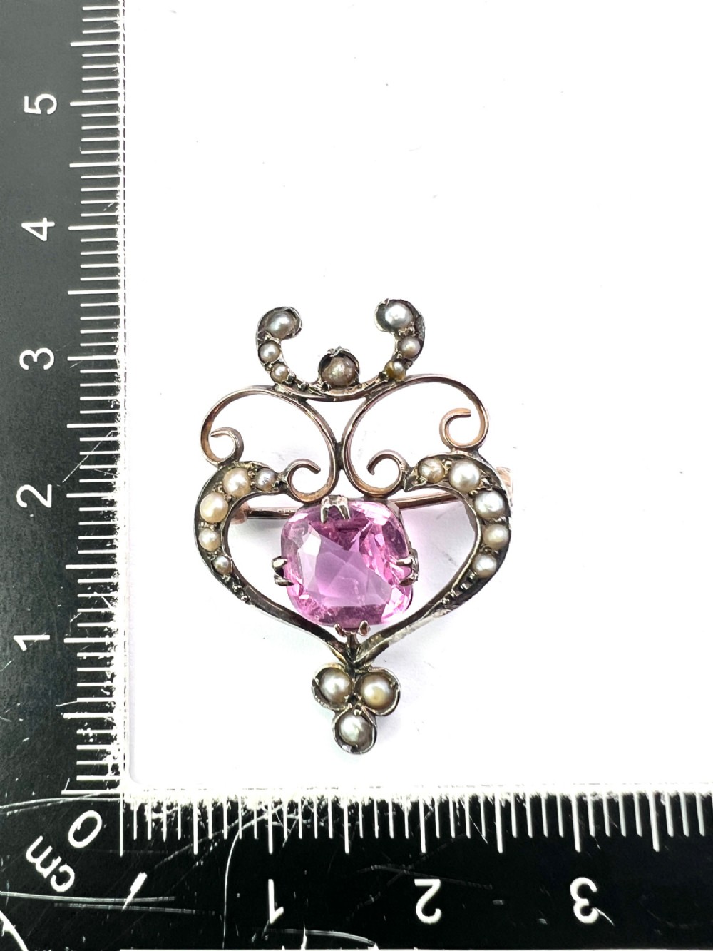 An Edwardian gold openwork scrollwork brooch featuring a central cushion-cut pink tourmaline surrounded by accent seed pearls. View IV
