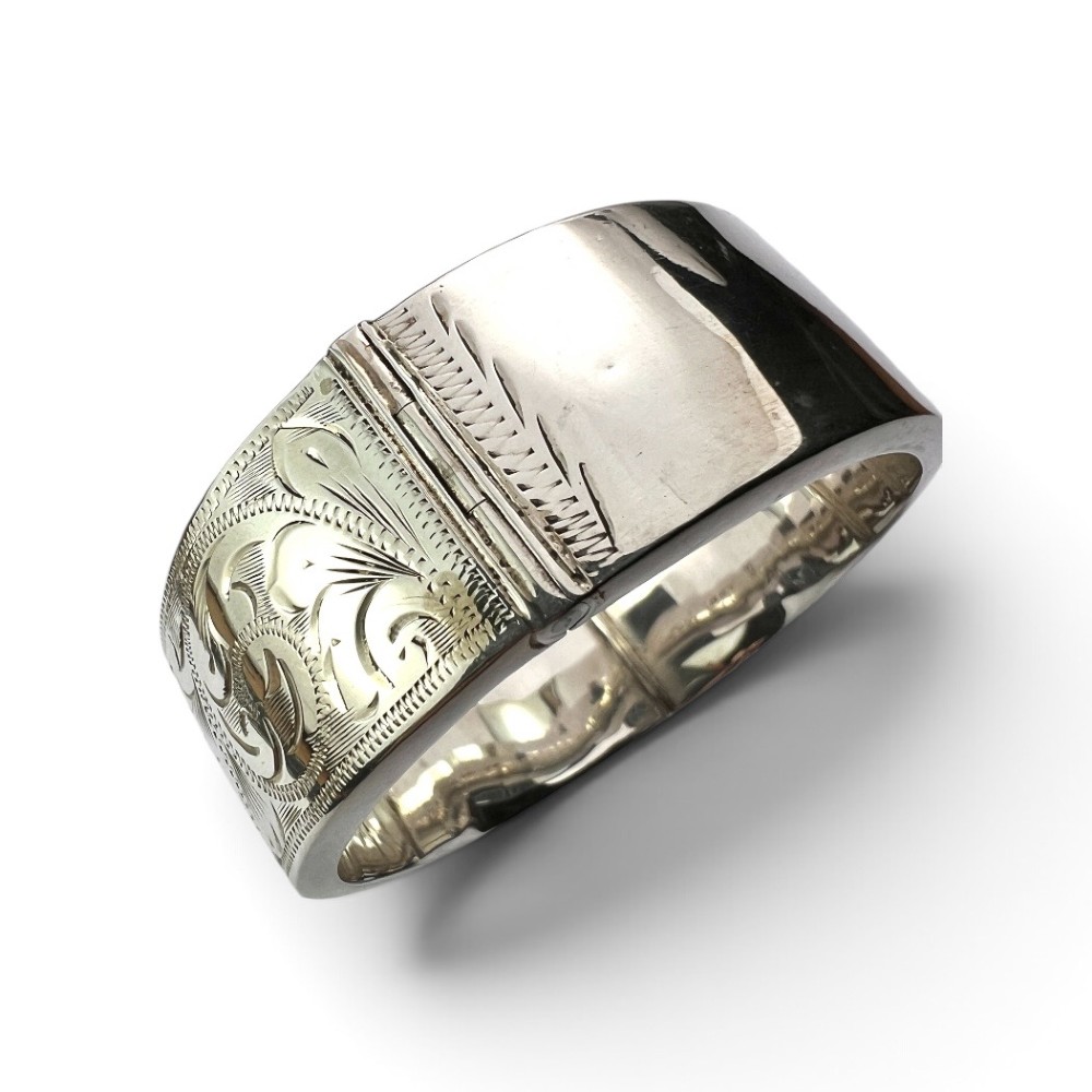 A wide sterling silver hinged bangle featuring detailed hand-engraved scrollwork and a polished inner finish. View IV