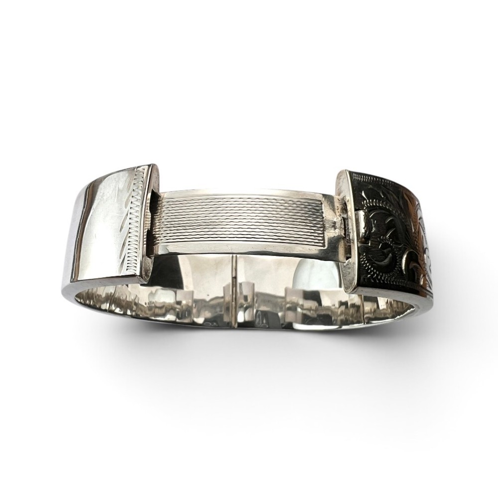 A wide sterling silver hinged bangle featuring detailed hand-engraved scrollwork and a polished inner finish. View V