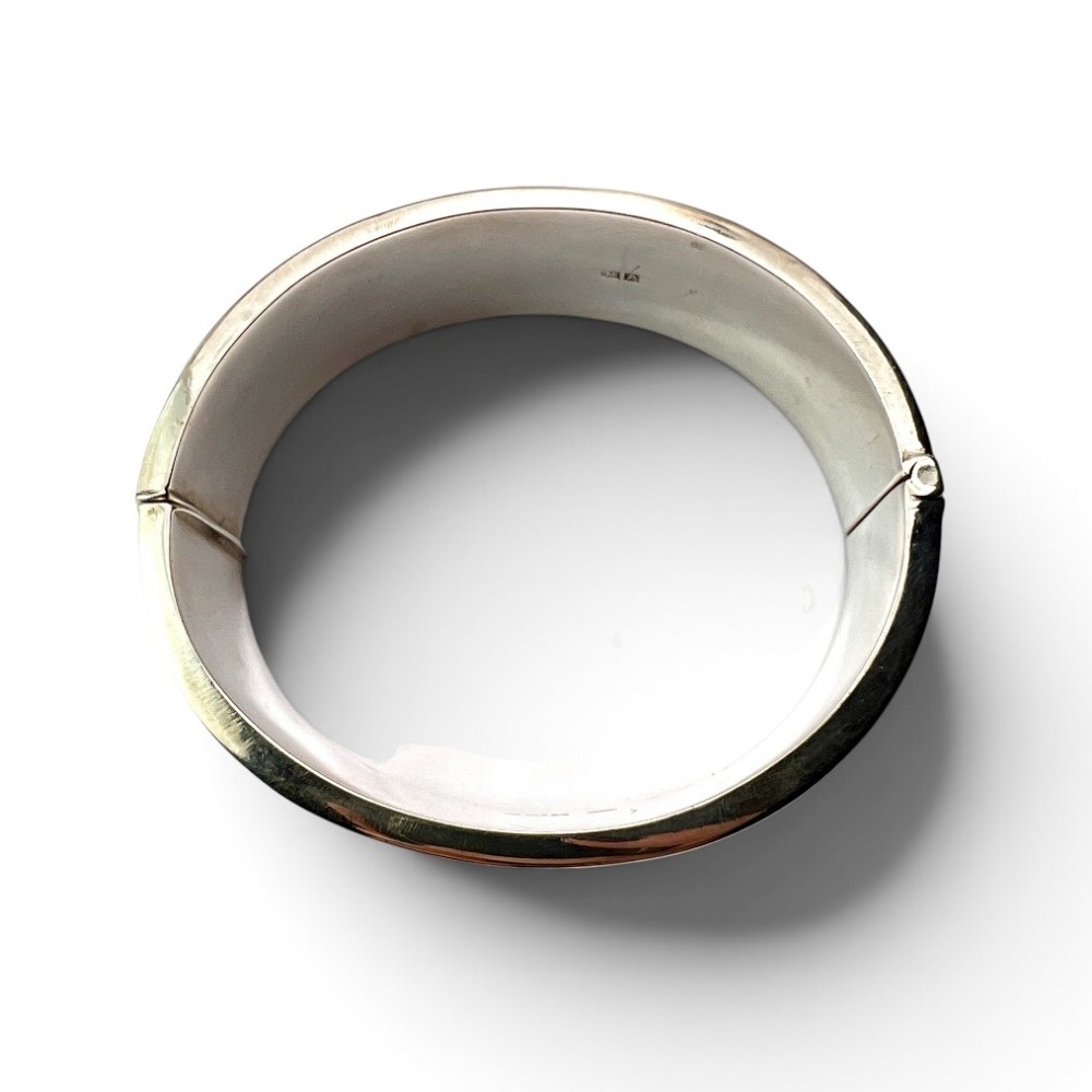 A wide sterling silver hinged bangle featuring detailed hand-engraved scrollwork and a polished inner finish. View VI