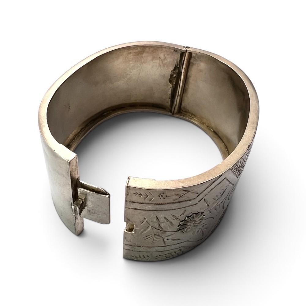 A wide Victorian sterling silver hinged cuff bangle featuring hand-engraved floral and geometric patterns across the exterior surface. View II