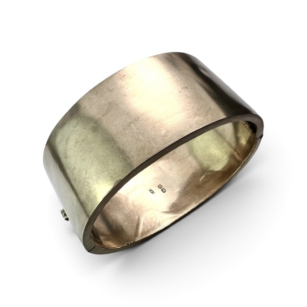 A wide Victorian sterling silver hinged cuff bangle featuring hand-engraved floral and geometric patterns across the exterior surface. View V