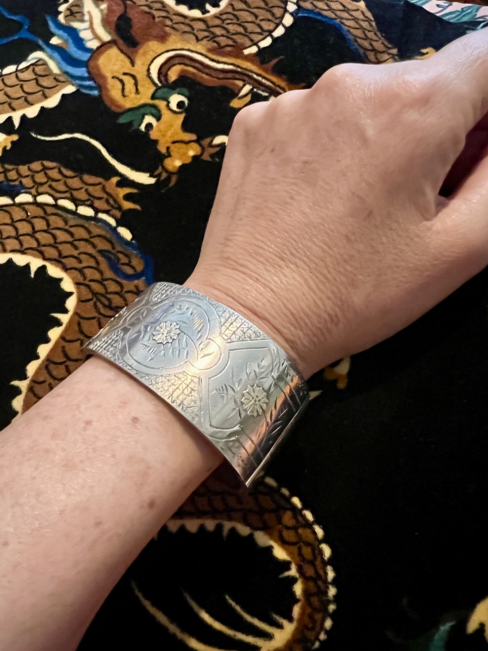 A wide Victorian sterling silver hinged cuff bangle featuring hand-engraved floral and geometric patterns across the exterior surface. View VIII