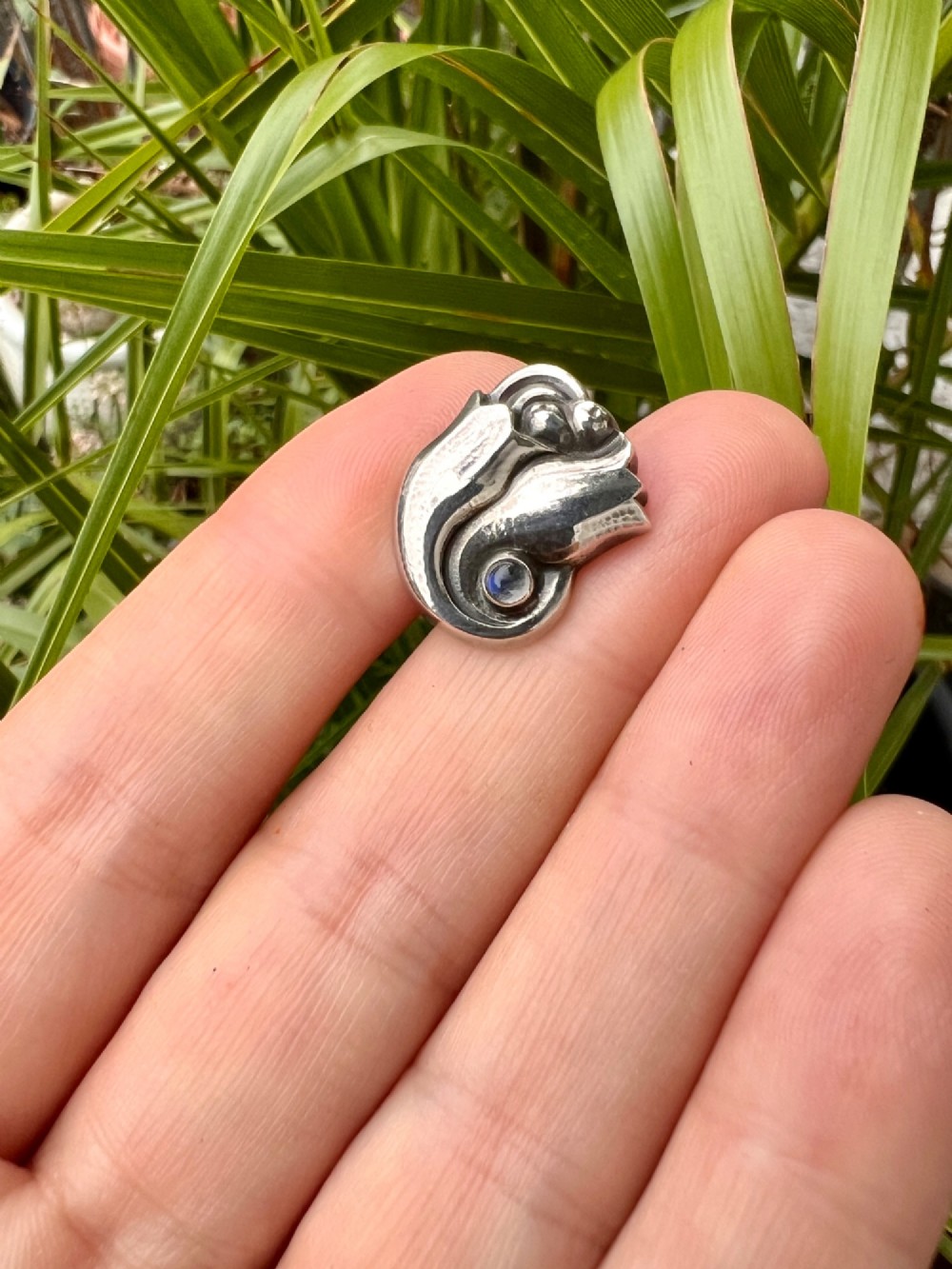 A single sterling silver stud earring shaped as a stylized tulip blossom with an inset round moonstone cabochon near the scroll base. View VI