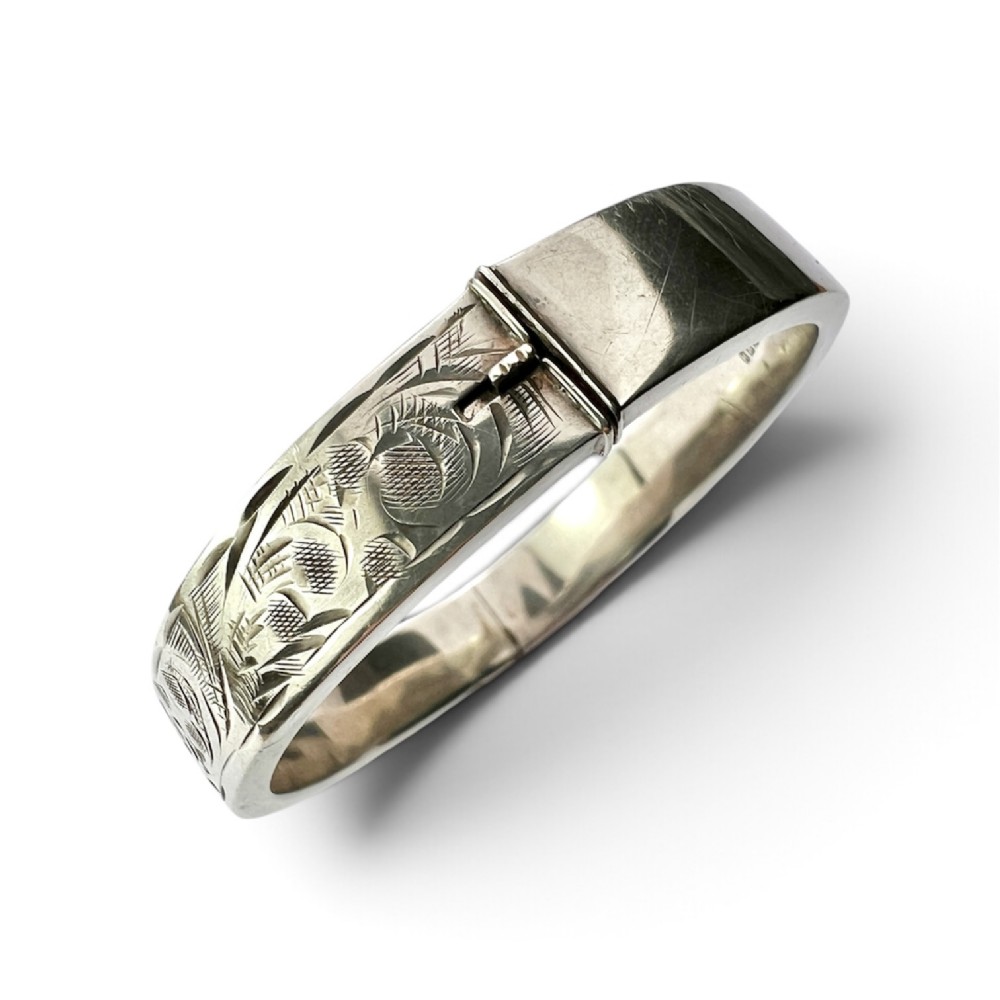 A sterling silver hinged bangle decorated with engraved foliate motifs and visible internal makers hallmarks. View II