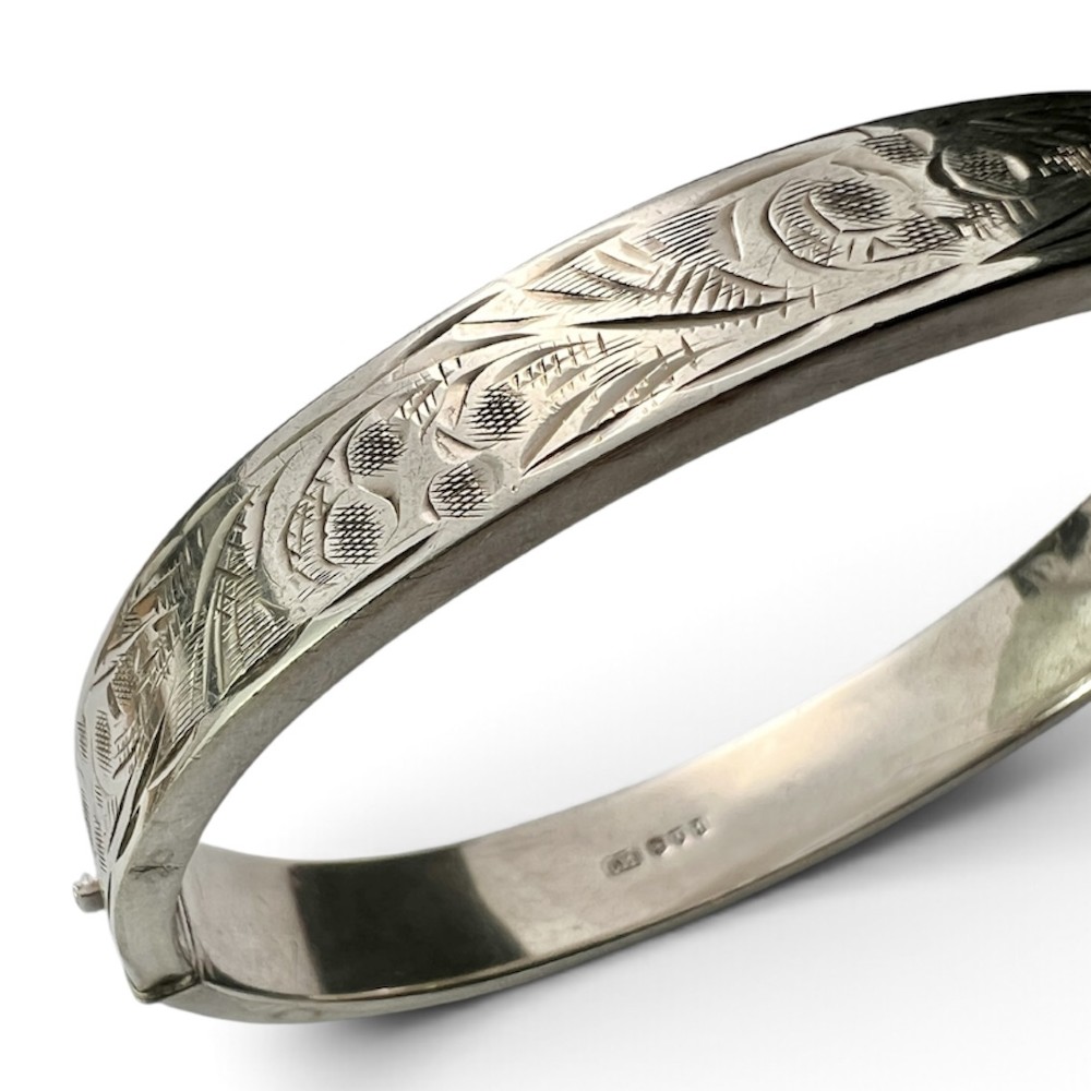 A sterling silver hinged bangle decorated with engraved foliate motifs and visible internal makers hallmarks. View IV