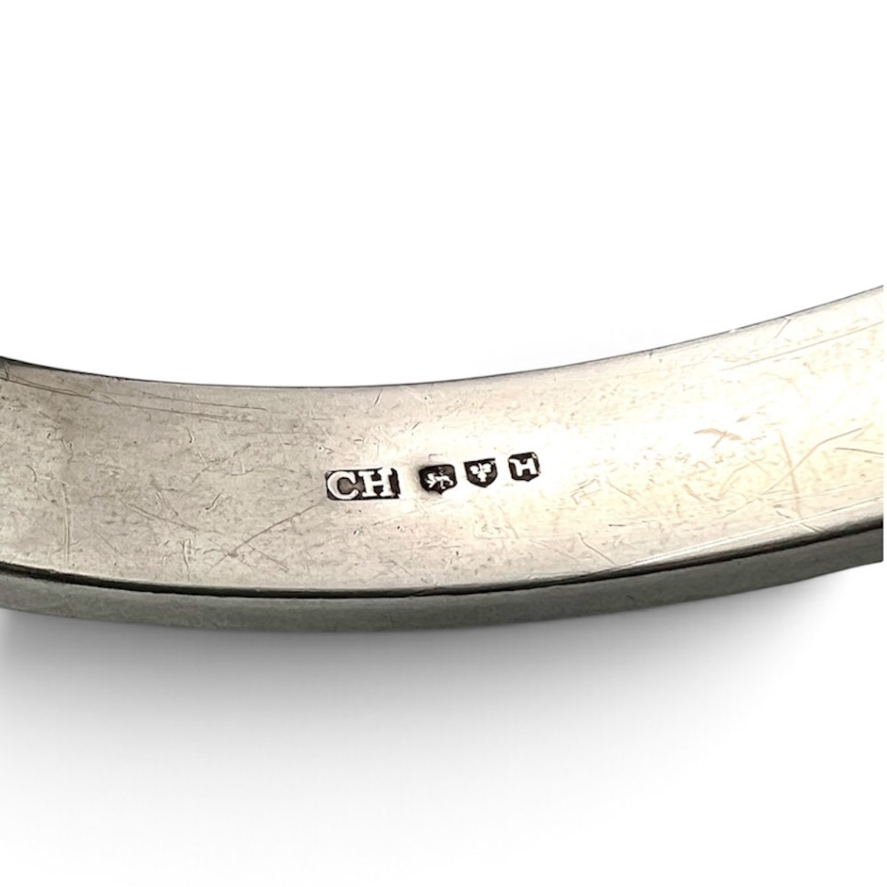 A sterling silver hinged bangle decorated with engraved foliate motifs and visible internal makers hallmarks. View VIII