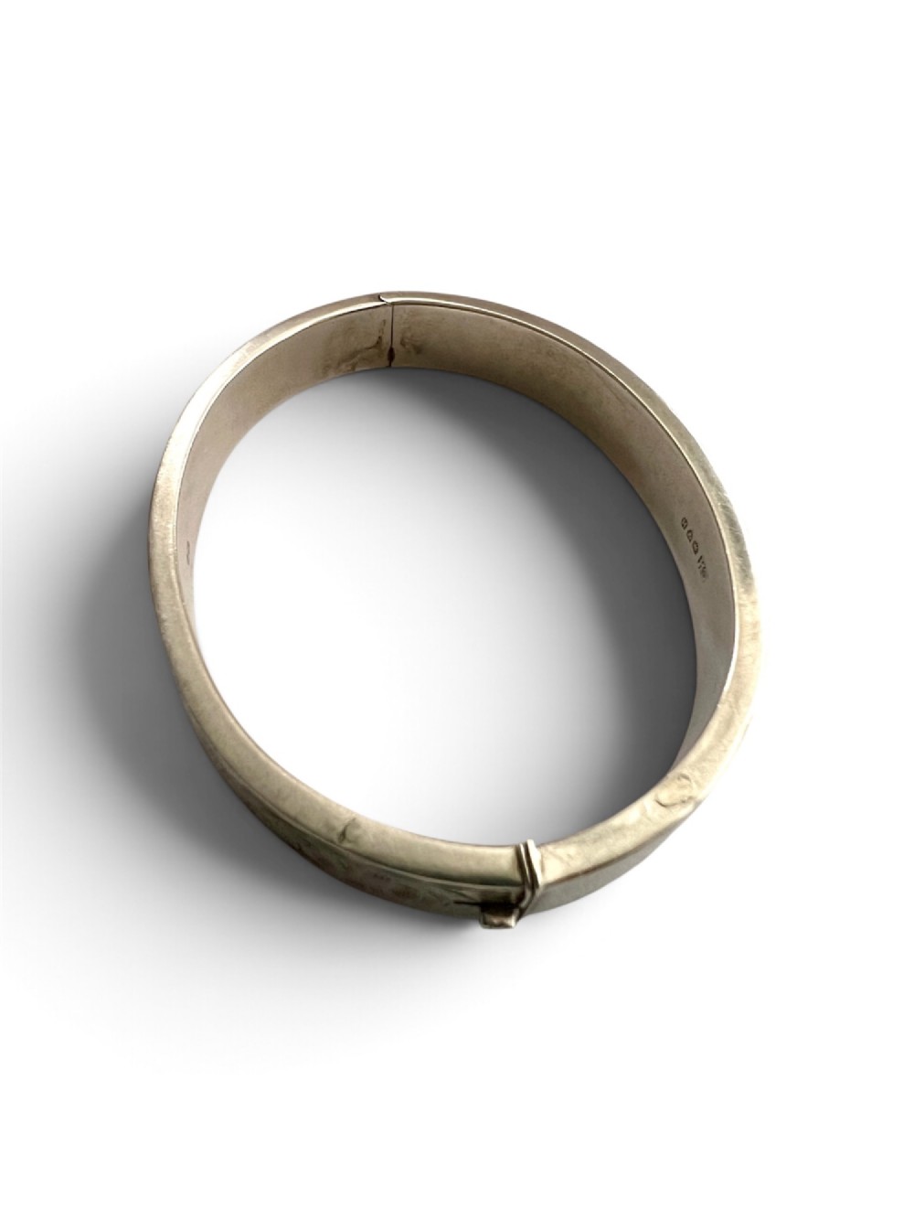 A sterling silver hinged bangle decorated with engraved foliate motifs and visible internal makers hallmarks. View IX