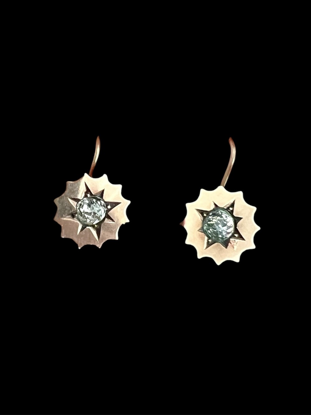 A pair of Victorian gold drop earrings featuring starburst-engraved settings with central clear round paste stones and shepherd hook fastenings. View V