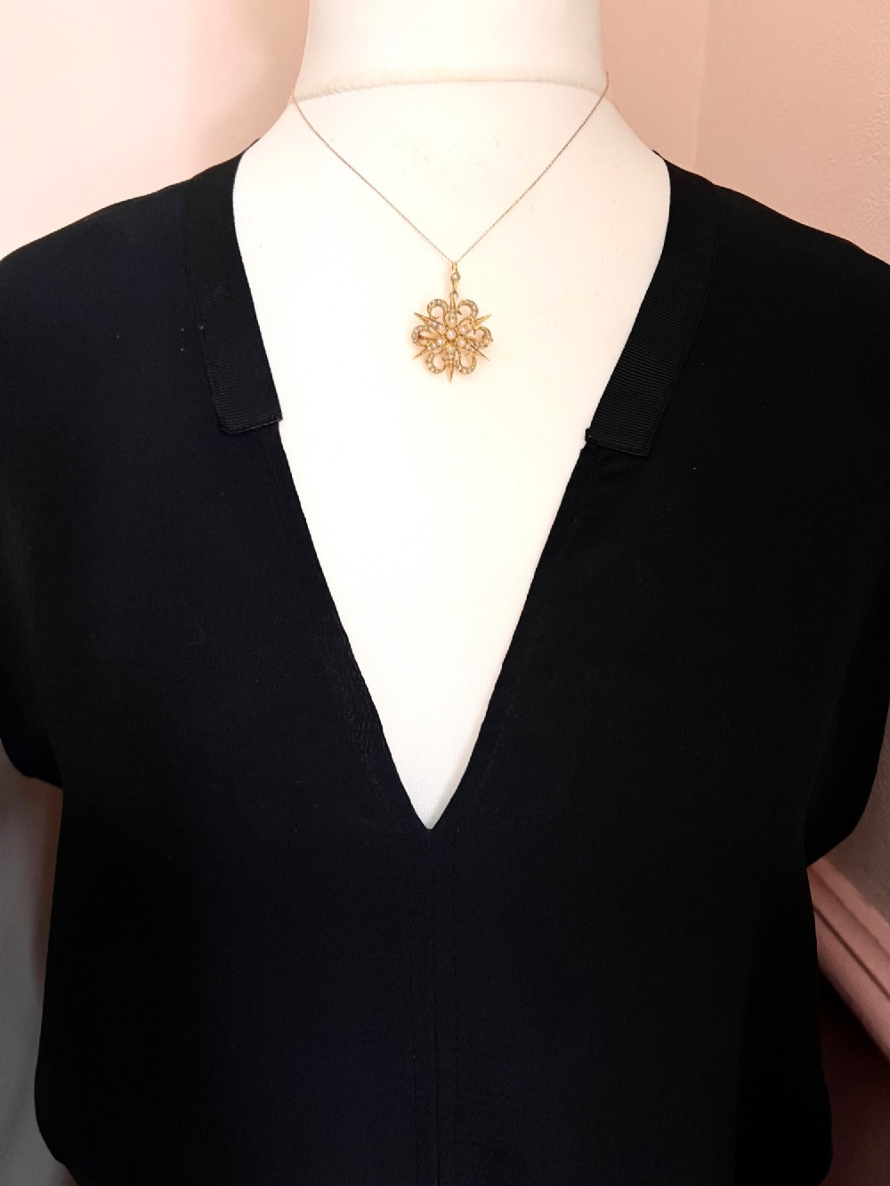 An antique 15ct yellow gold sunburst pendant brooch set with seed pearls arranged in a celestial starburst and scroll motif. View V