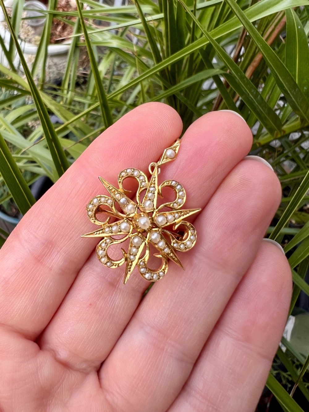 An antique 15ct yellow gold sunburst pendant brooch set with seed pearls arranged in a celestial starburst and scroll motif. View VI