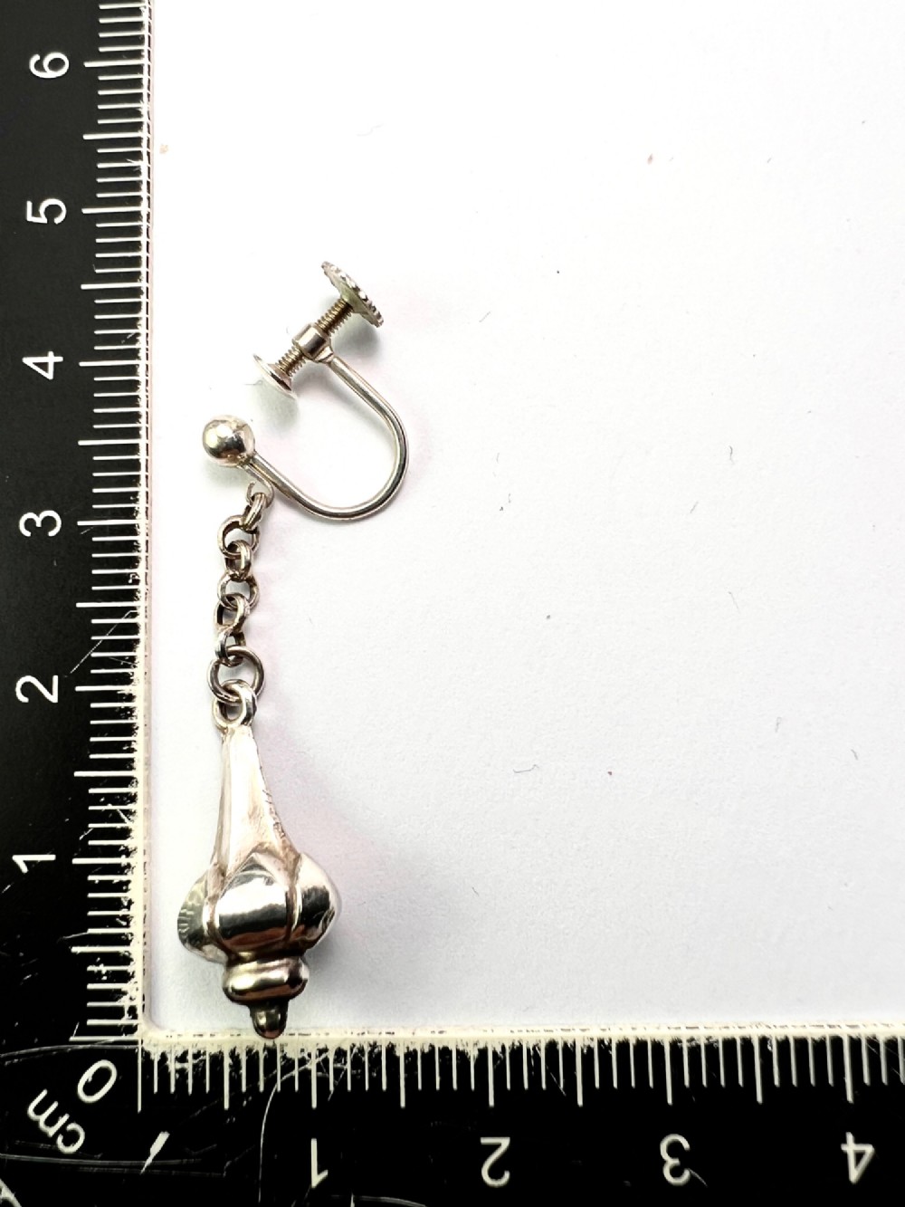 A pair of sterling silver drop earrings featuring screw-back fastenings, chain links, and ribbed lotus bud pendants. View VI