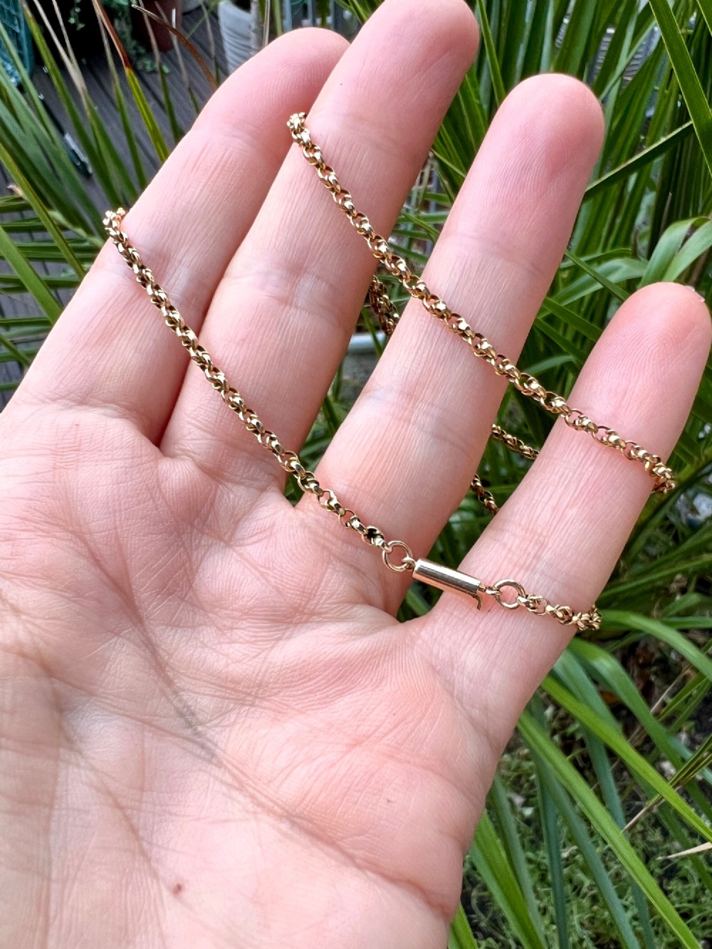 An Edwardian 9ct gold chain necklace coiled flat against a neutral white background displaying rope links and a cylindrical clasp. View VIII