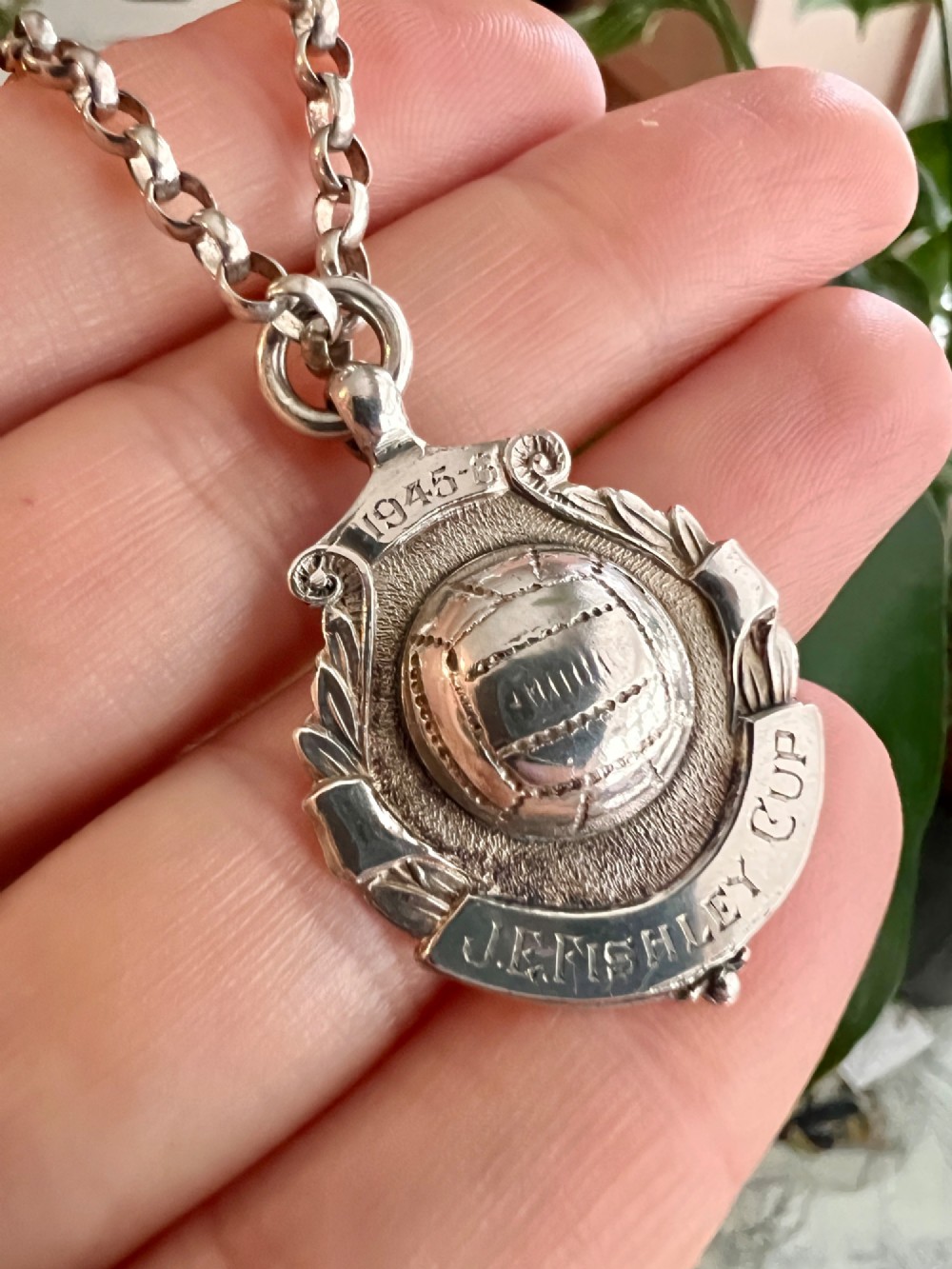 A sterling silver chain necklace featuring a shield-shaped football medal pendant engraved with 1945-6 and JR Fishley Cup. View V