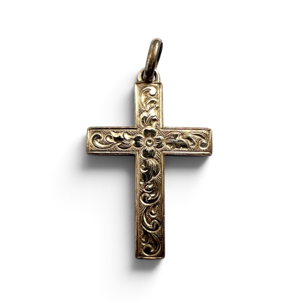 A Victorian rolled gold cross pendant featuring hand-engraved floral and scrollwork motifs with a suspension loop at the top.