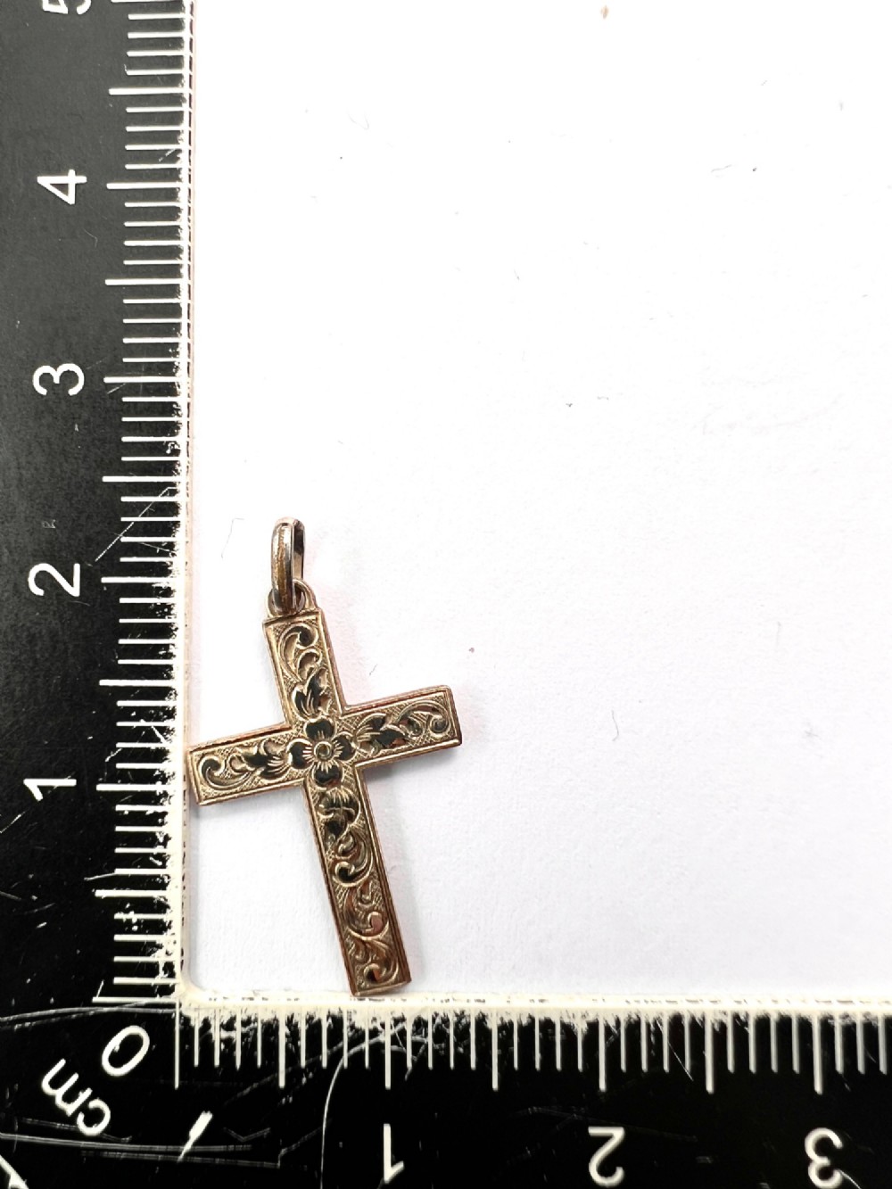 A Victorian rolled gold cross pendant featuring hand-engraved floral and scrollwork motifs with a suspension loop at the top. View V