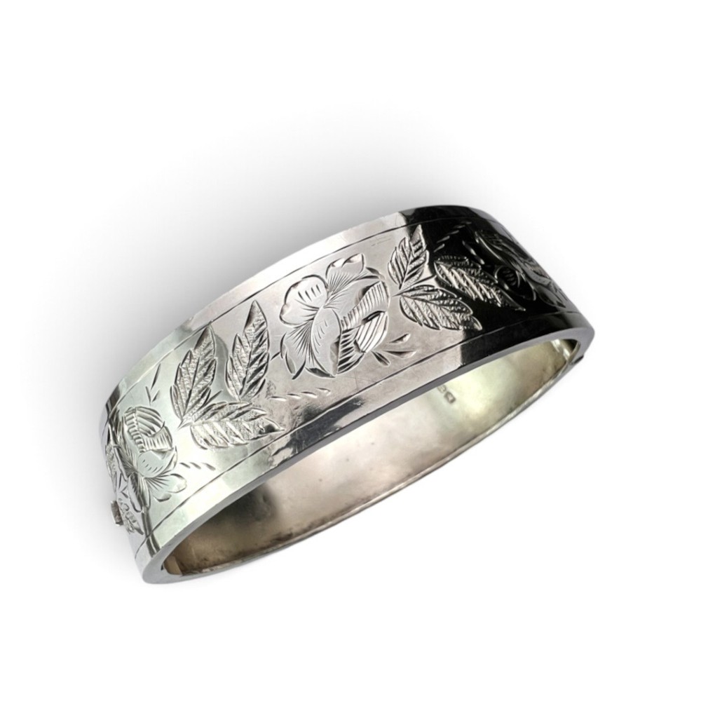 An antique Victorian sterling silver hinged bangle with hand-engraved floral and leaf motifs and interior hallmarks. View II