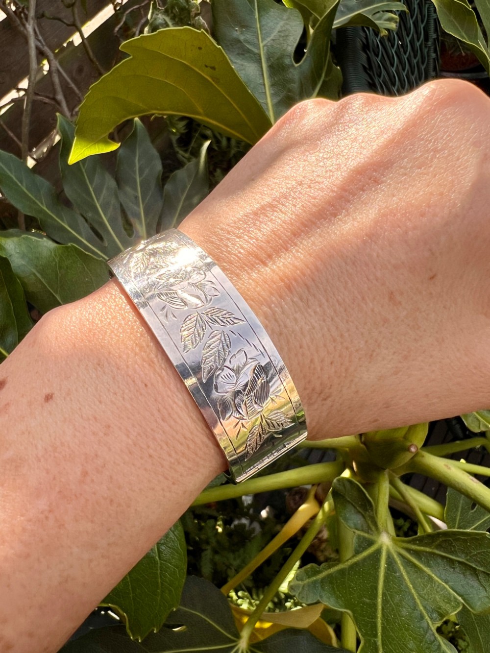 An antique Victorian sterling silver hinged bangle with hand-engraved floral and leaf motifs and interior hallmarks. View IX