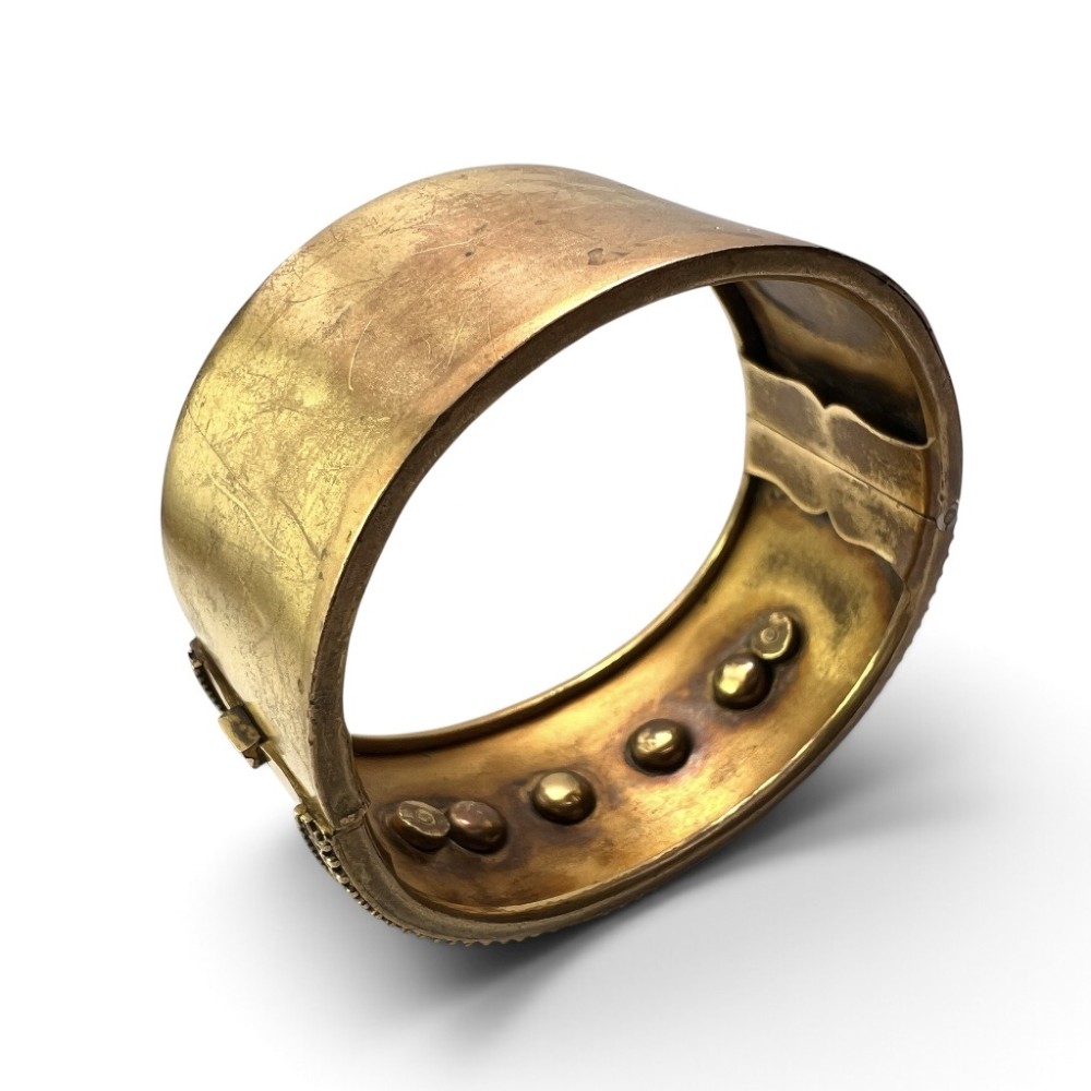A wide Victorian Etruscan Revival gold hinged bangle decorated with intricate beadwork borders and star-set gemstones across a central band. View VI