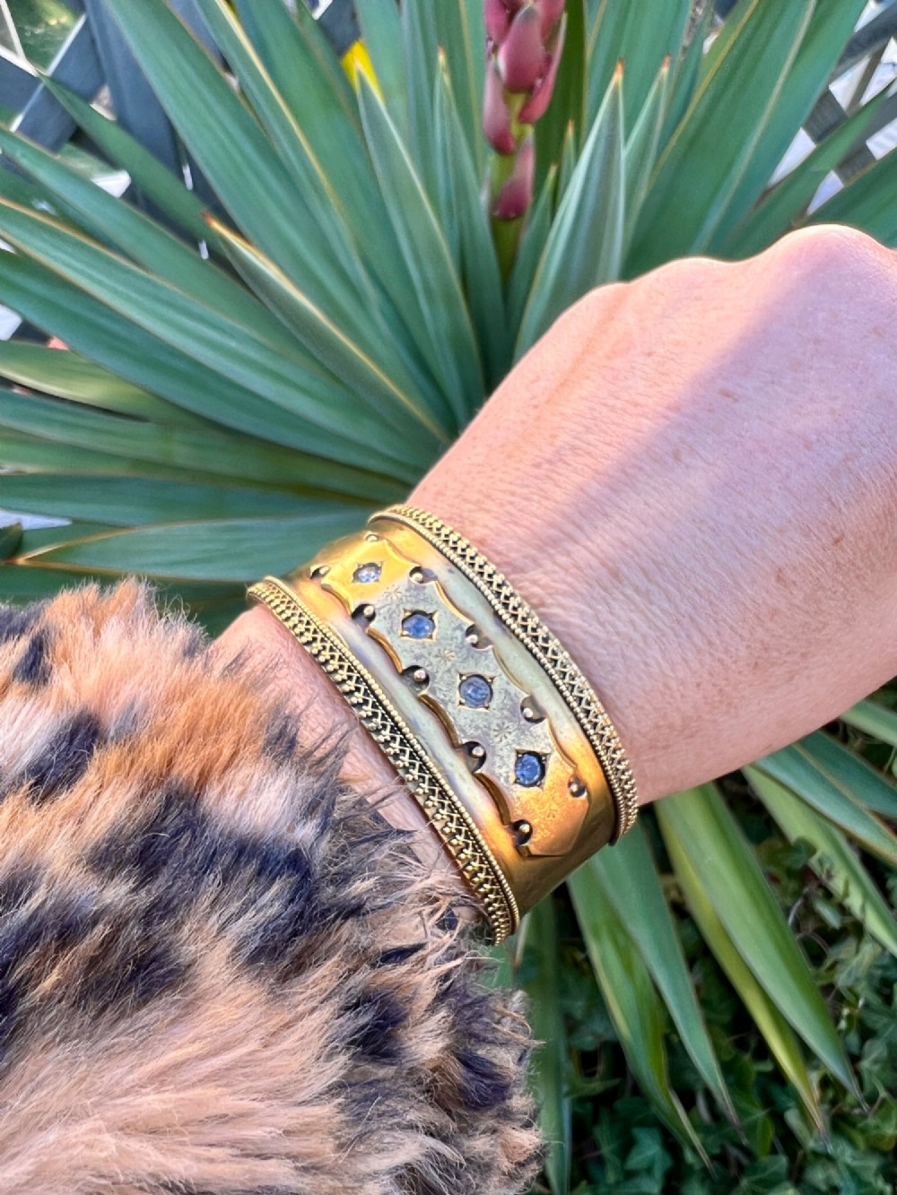 A wide Victorian Etruscan Revival gold hinged bangle decorated with intricate beadwork borders and star-set gemstones across a central band. View IX