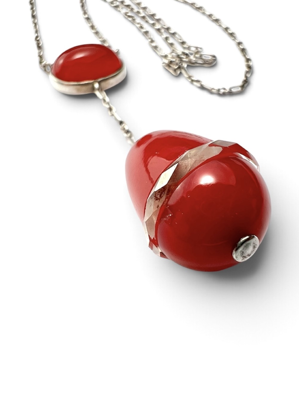 An Edwardian silver lavalier necklace featuring an oval red stone cabochon and an egg-shaped red pendant bound by a silver band. View II