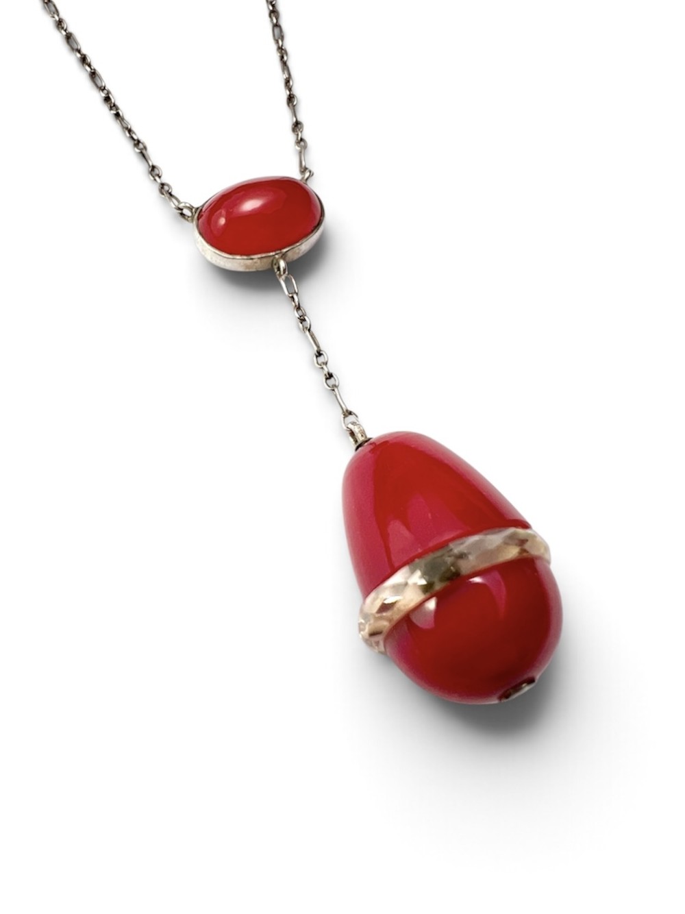 An Edwardian silver lavalier necklace featuring an oval red stone cabochon and an egg-shaped red pendant bound by a silver band. View IV