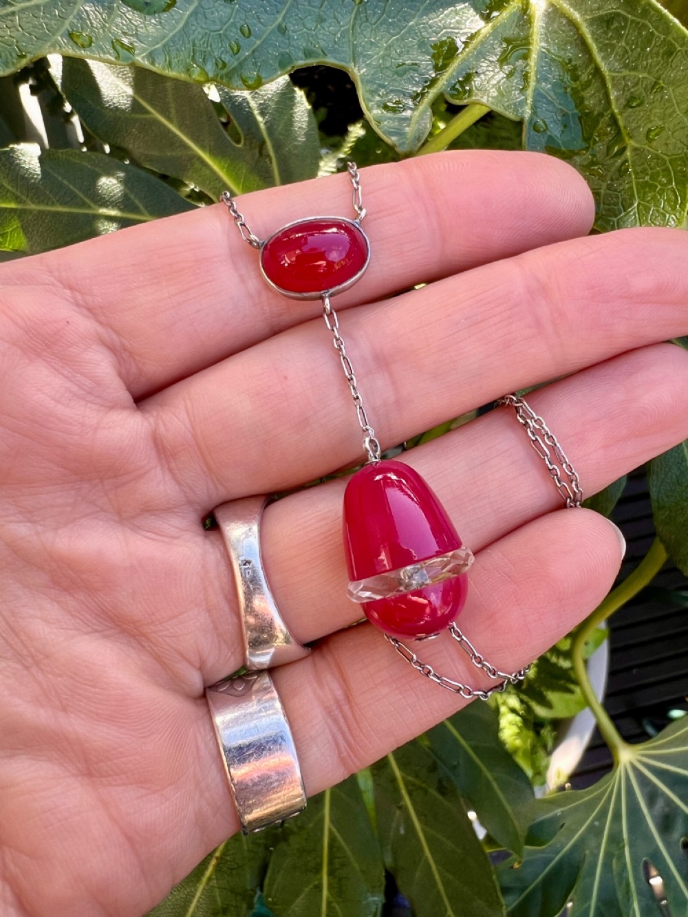 An Edwardian silver lavalier necklace featuring an oval red stone cabochon and an egg-shaped red pendant bound by a silver band. View VI
