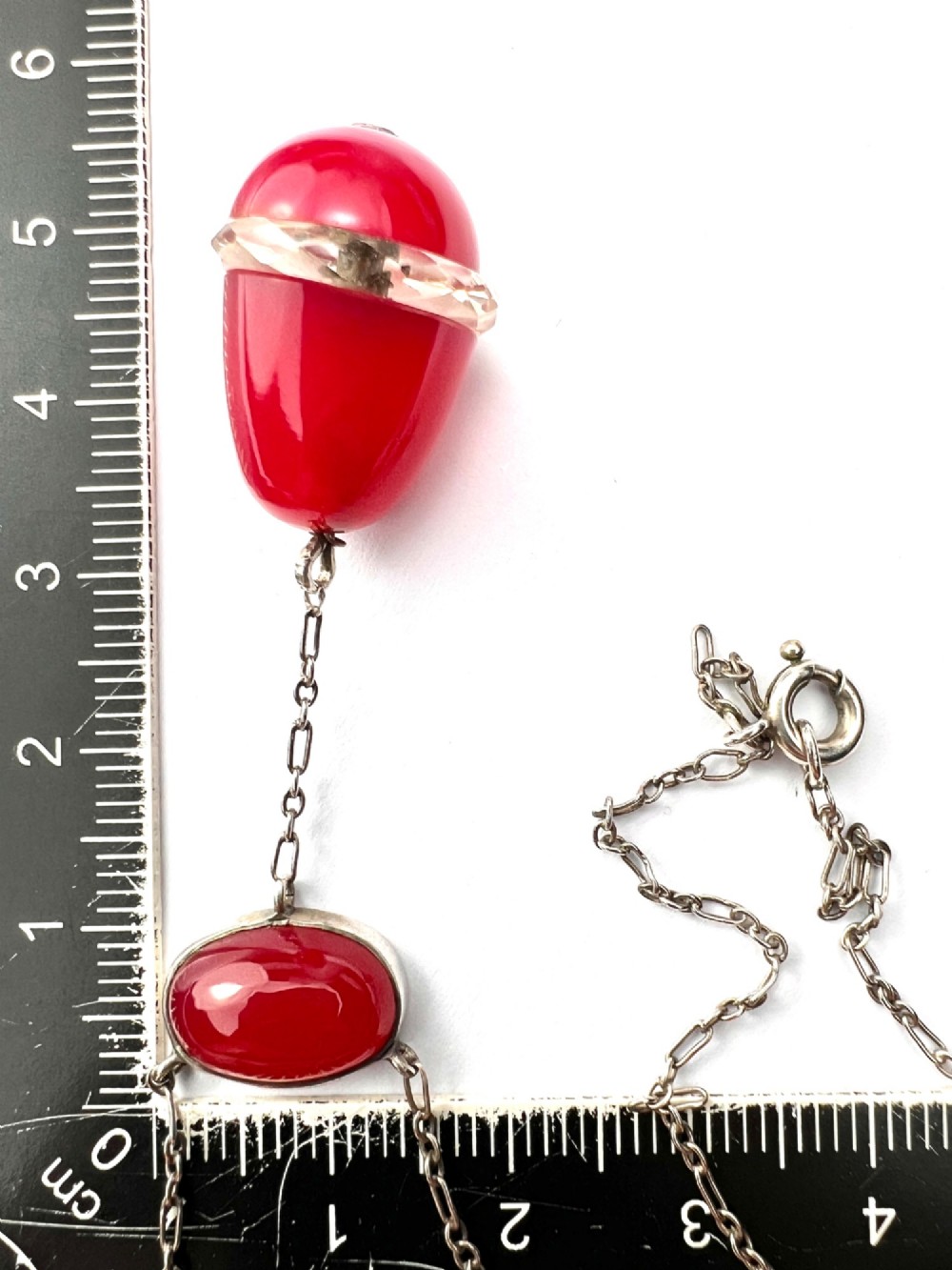 An Edwardian silver lavalier necklace featuring an oval red stone cabochon and an egg-shaped red pendant bound by a silver band. View VII