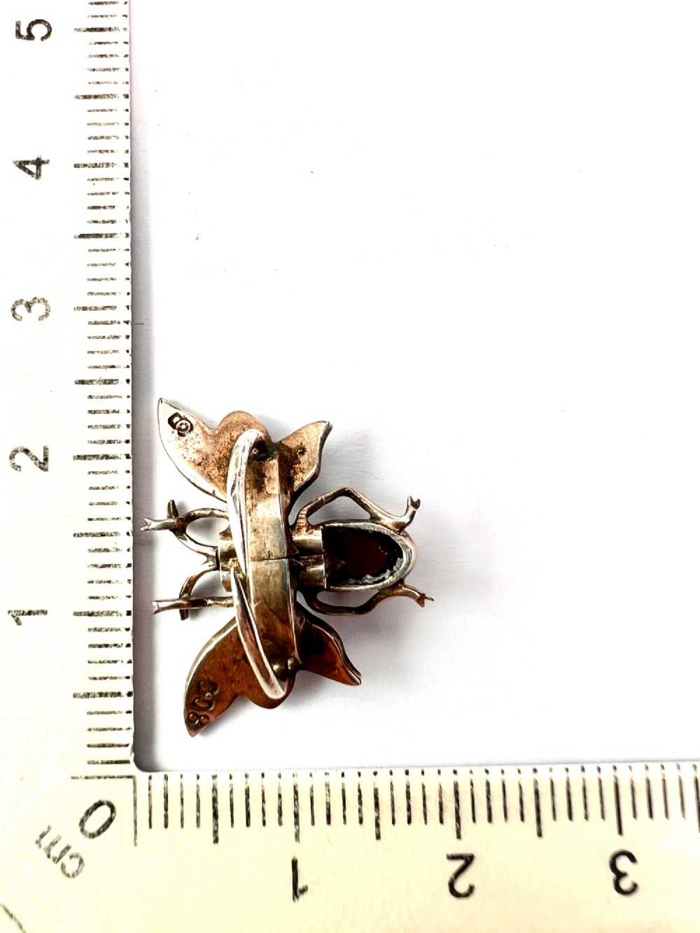 A Victorian silver gilt brooch shaped like an insect, featuring a cabochon red garnet body and wings accented with small seed pearls. View VIII