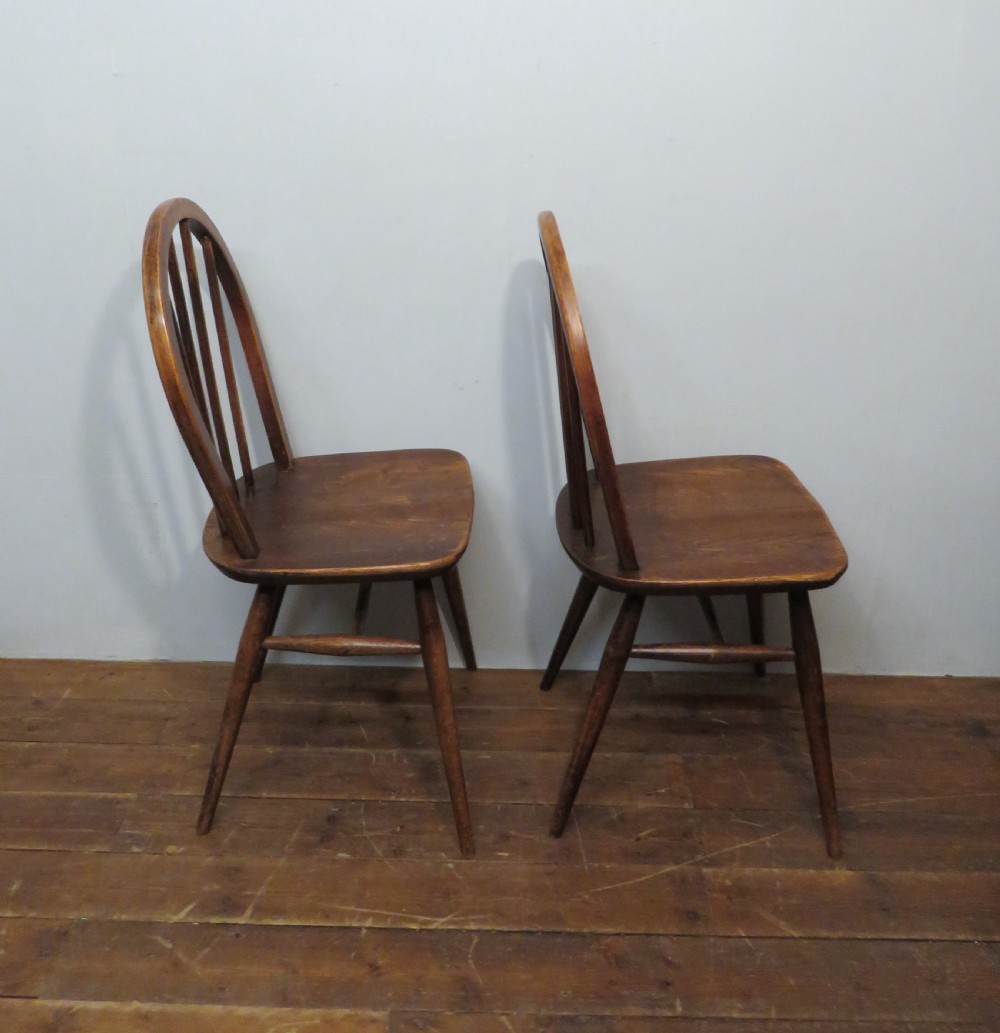 A pair of warm brown wooden dining chairs featuring hoop-shaped spindle backs, contoured elm seats, and splayed legs. View II