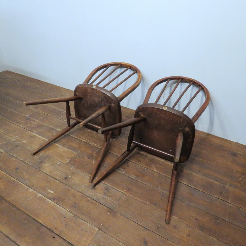 A pair of warm brown wooden dining chairs featuring hoop-shaped spindle backs, contoured elm seats, and splayed legs. View XIV