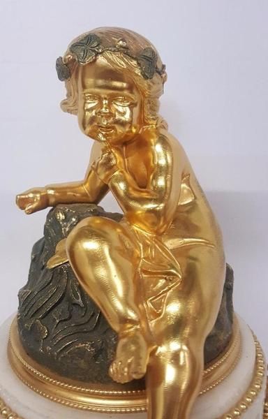 fig 2. A 19th-century French white marble mantel clock decorated with gilded ormolu mounts and topped with a seated cherub figure.