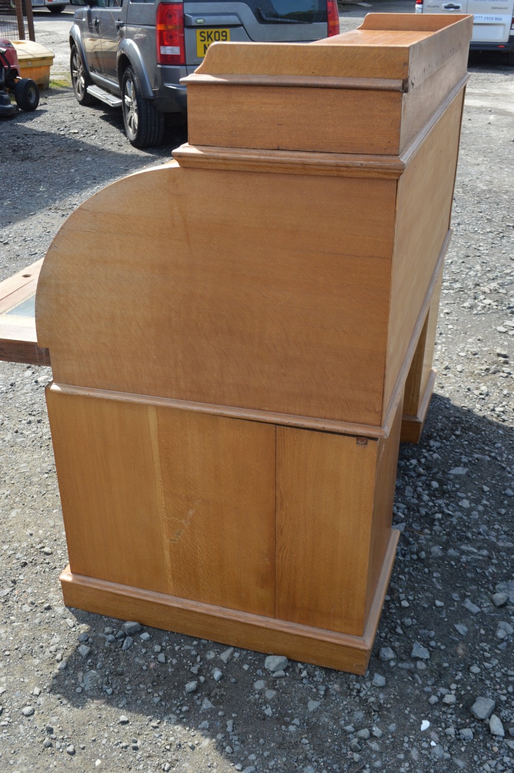 An antique Victorian light oak cylinder desk with a curved roll-top front, twin pedestals containing drawers, and a raised top gallery. View III