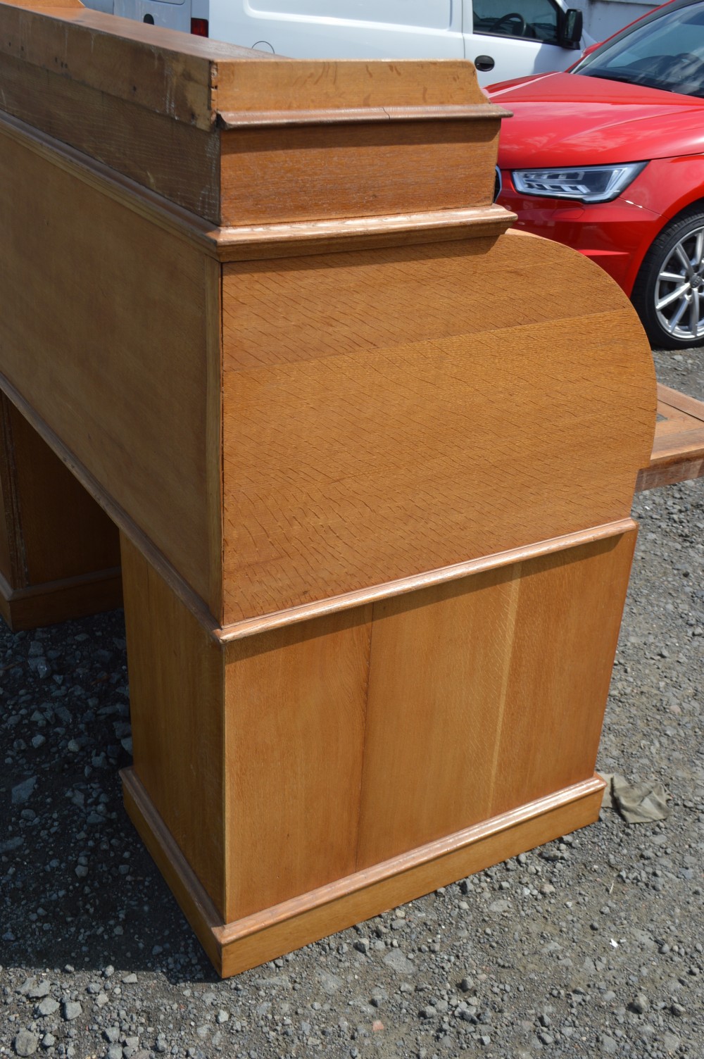 An antique Victorian light oak cylinder desk with a curved roll-top front, twin pedestals containing drawers, and a raised top gallery. View V