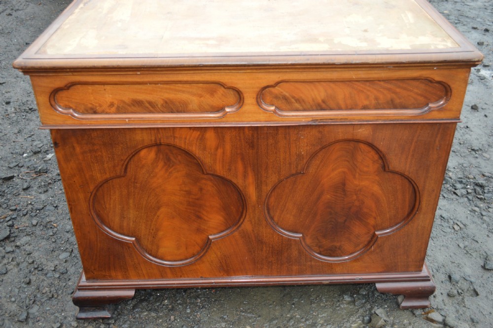 A Victorian mahogany partners desk featuring twin pedestal bases with carved fielded panels and frieze drawers with brass handles. View II