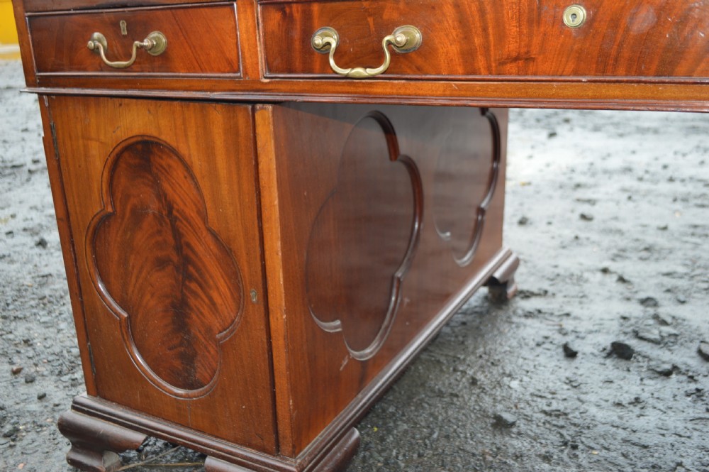 A Victorian mahogany partners desk featuring twin pedestal bases with carved fielded panels and frieze drawers with brass handles. View III