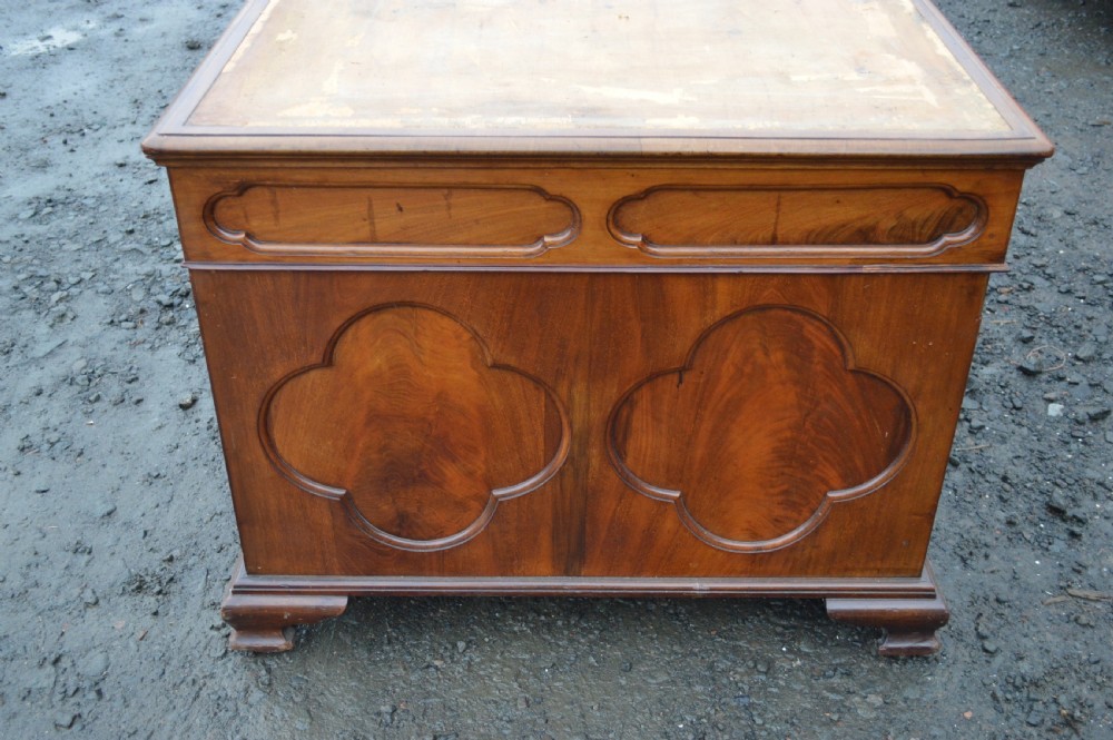 A Victorian mahogany partners desk featuring twin pedestal bases with carved fielded panels and frieze drawers with brass handles. View IV