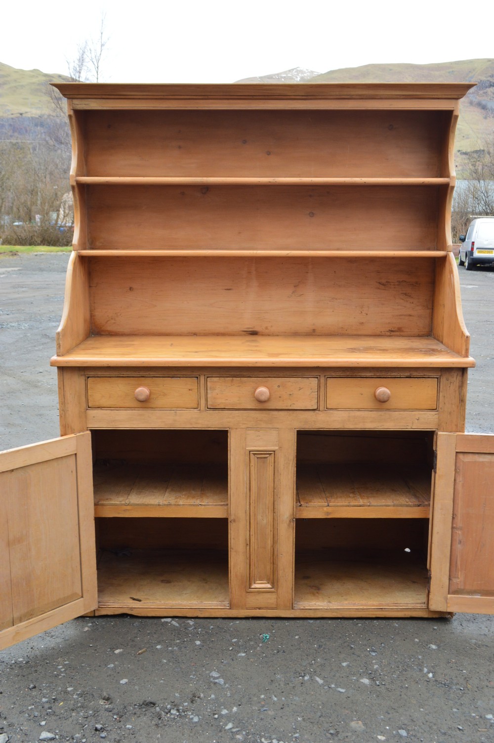 A Victorian Scots pine dresser featuring an upper open-shelf display rack above a base with three drawers and lower double cupboard doors.