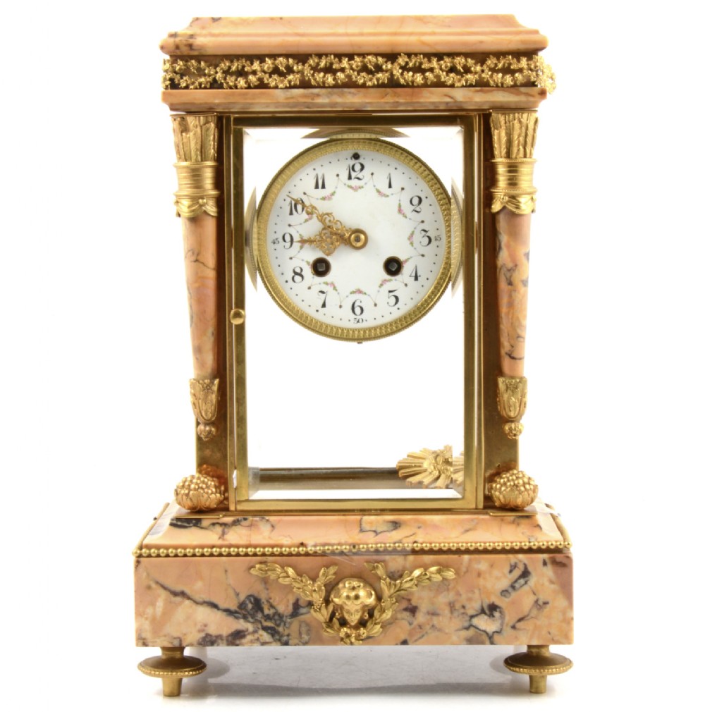 A 19th-century French four-glass mantel clock featuring a pink marbled stone casing with gilded bronze mounts and a white enamel clock dial.
