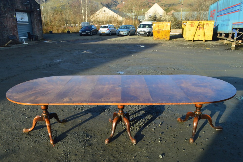 A George III style extendable dining table made of figured walnut with three turned pedestal bases and tripod legs. View IV