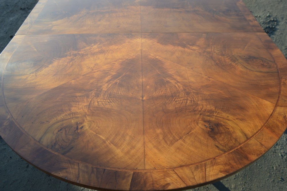 A George III style extendable dining table made of figured walnut with three turned pedestal bases and tripod legs. View IX