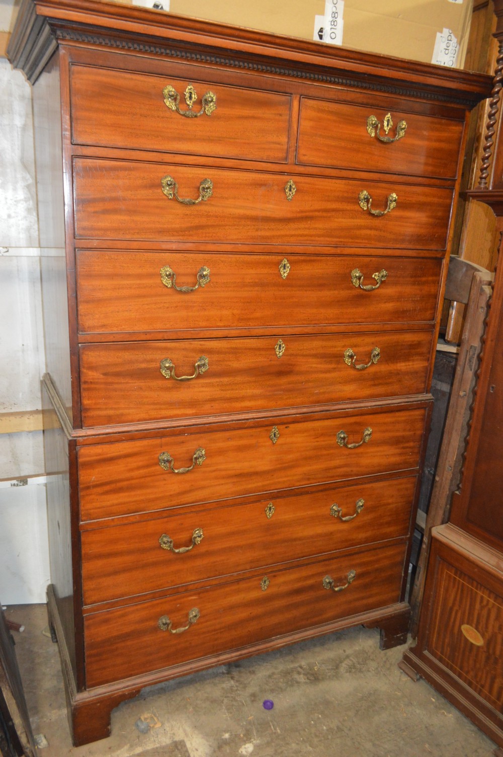 An antique Georgian mahogany chest-on-chest featuring two short drawers over six long graduated drawers with brass swan-neck handles and bracket feet.