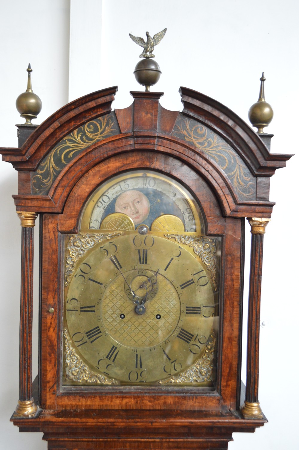 An 18th-century pollard oak longcase clock with an arched hood, brass eagle finial, and engraved brass dial. View II