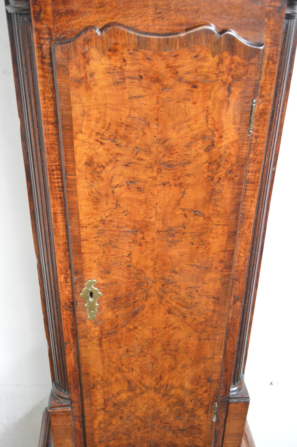 An 18th-century pollard oak longcase clock with an arched hood, brass eagle finial, and engraved brass dial. View V