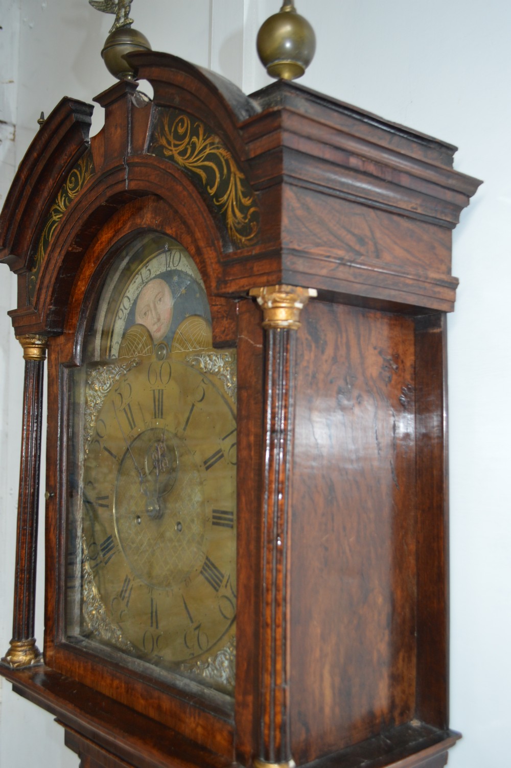 An 18th-century pollard oak longcase clock with an arched hood, brass eagle finial, and engraved brass dial. View VII