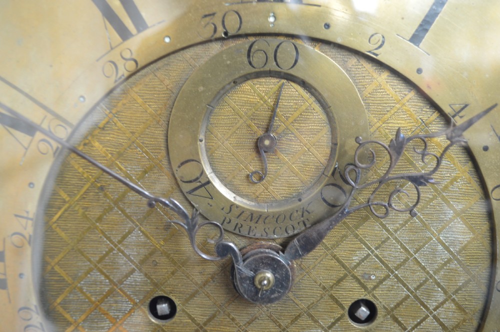 An 18th-century pollard oak longcase clock with an arched hood, brass eagle finial, and engraved brass dial. View IX